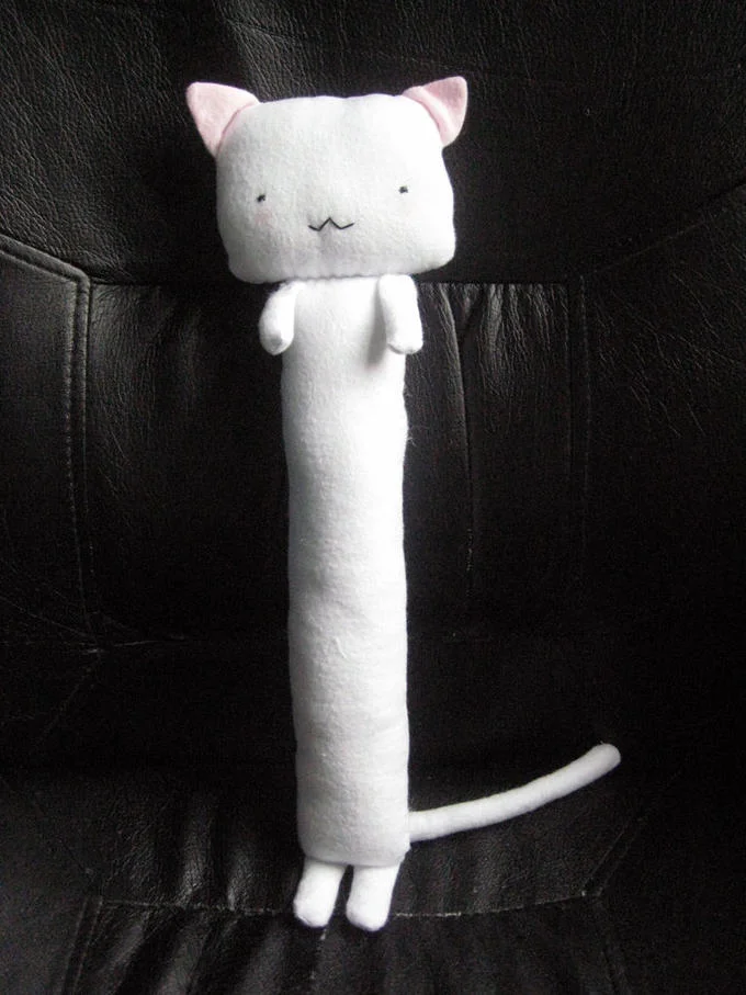 A tall white snow sculpture of the Longcat face with coal eyes and carrot nose, standing vertically outdoors in winter.