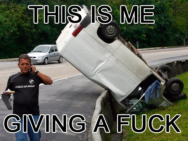 Look At All The Fucks I Give — Man on phone walking past an overturned car with the caption 'This is me giving a fuck'