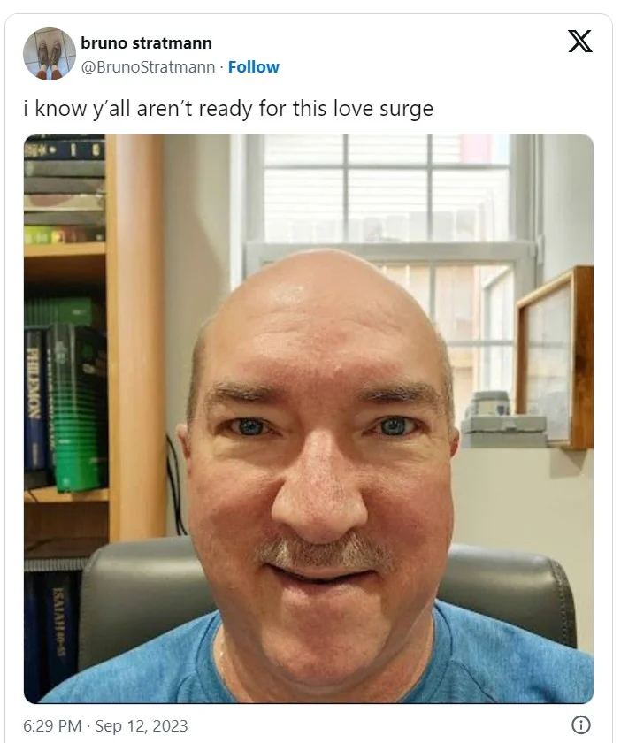 Tweet reading 'i know y'all aren't ready for this love surge' with a selfie of a middle-aged bald man at a desk