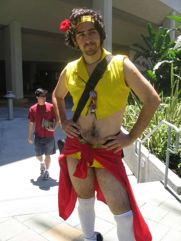 Man-Faye posing in fighting stance wearing yellow shorts and red shirt at convention