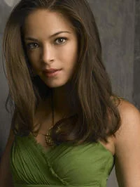 Mary Sue — A professional portrait photograph of a young brunette woman wearing a green top with neutral studio-style lighting.