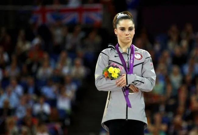 McKayla Maroney is Not Impressed — McKayla Maroney standing on Olympic podium with bouquet, arms crossed, looking unimpressed