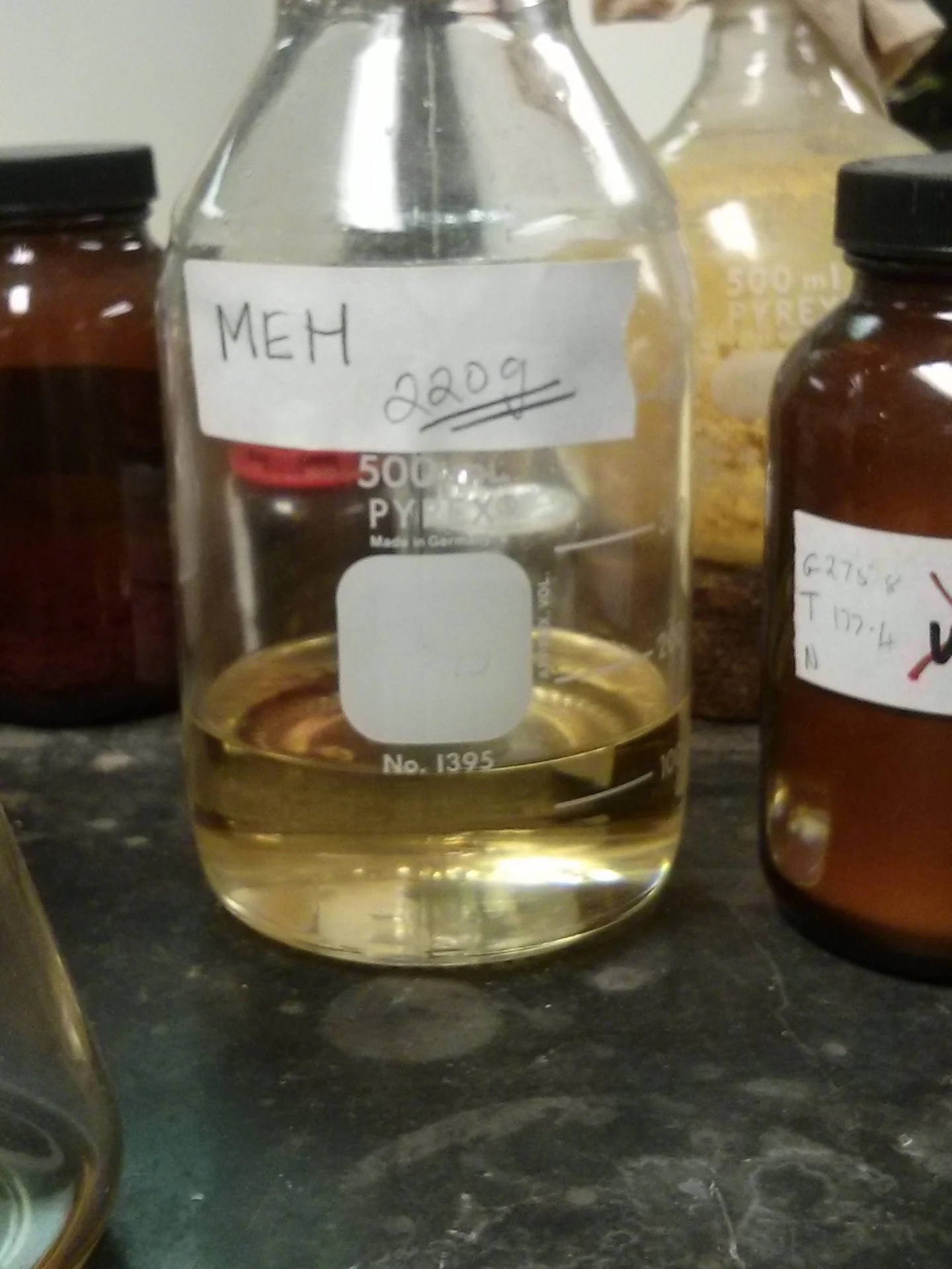 Meh. — Chemistry lab Pyrex bottle labeled 'MEH 220g' in handwriting, containing yellow liquid.