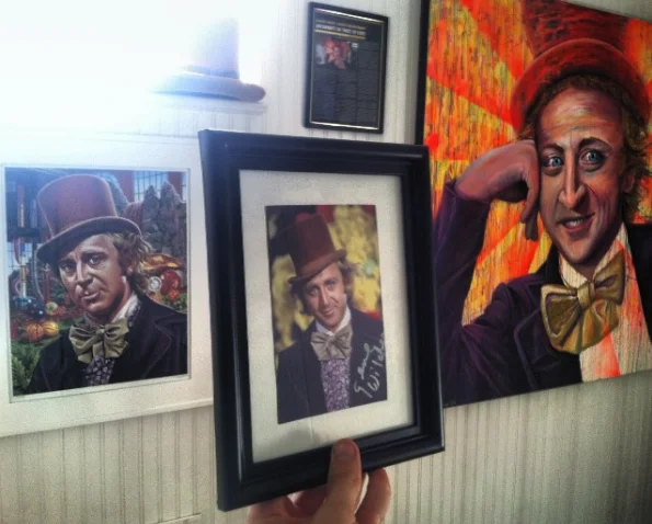Meme Paintings — Photograph of Willy Wonka paintings on a wall with a framed autograph