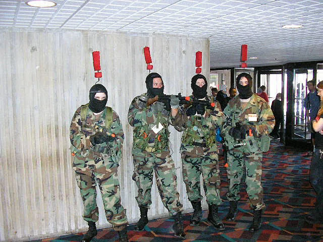 Metal Gear Solid Enemy Alert — Four soldiers in camouflage uniforms and gas masks wearing red exclamation marks above their heads in cosplay recreation.