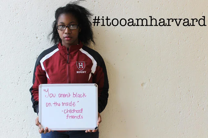 Microaggression — Black Harvard student holding sign 'You aren't black on the inside' with #itooamharvard hashtag