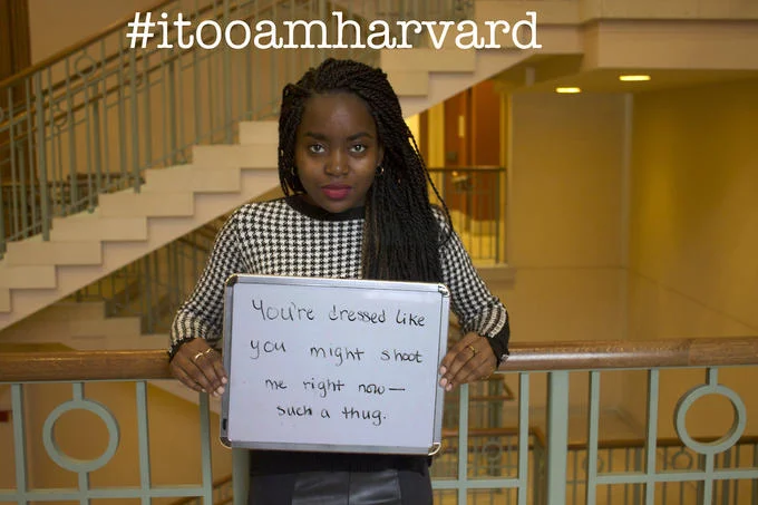 Microaggression — Black woman on stairs holding sign about being called a thug, with #itooamharvard hashtag