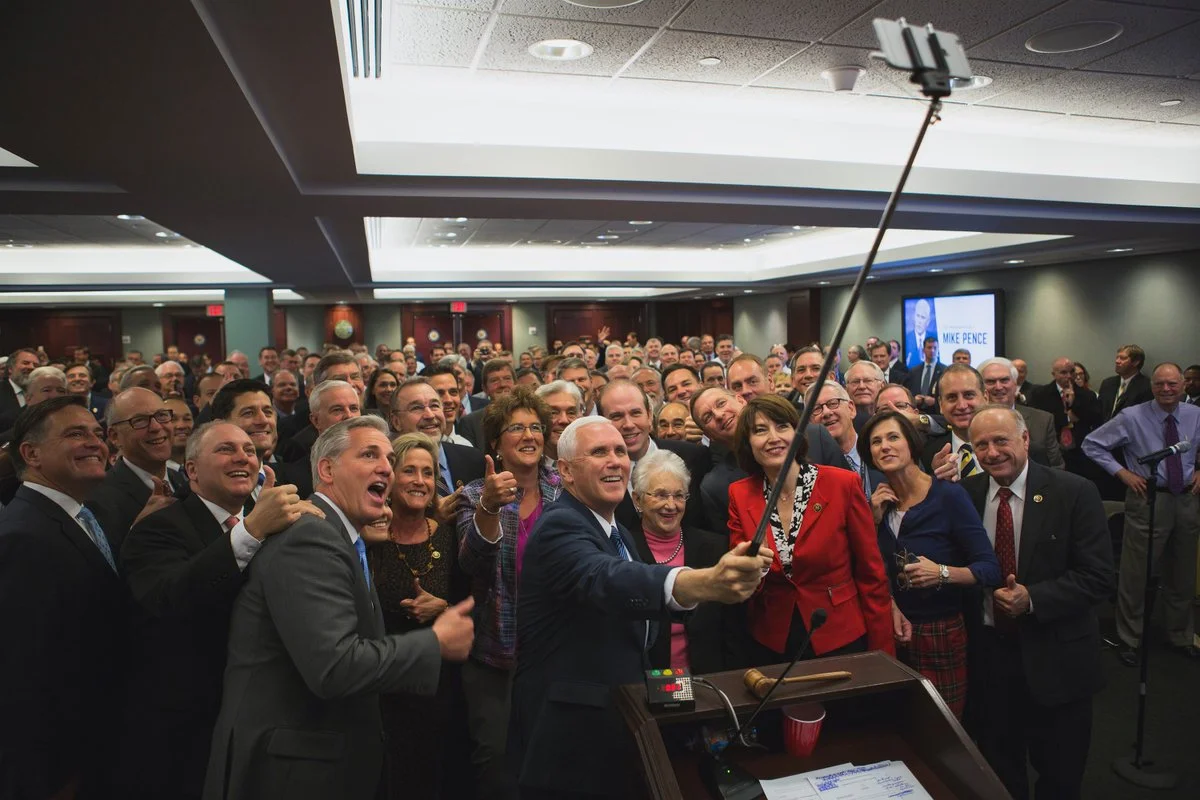 Mike Pence holding a selfie stick to photograph House Republicans