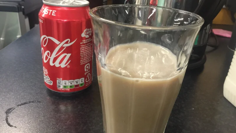 Milk Coke Debate — Glass of milk mixed with Coca-Cola beside a Coke can on a counter