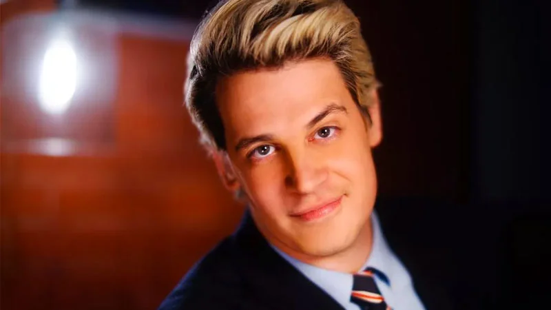 Portrait of Milo Yiannopoulos in a suit and striped tie