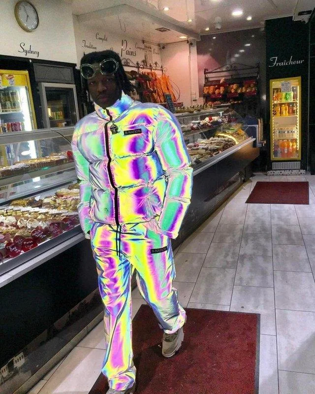 Minecraft Armor Parodies — Man in iridescent holographic tracksuit posing inside a bakery