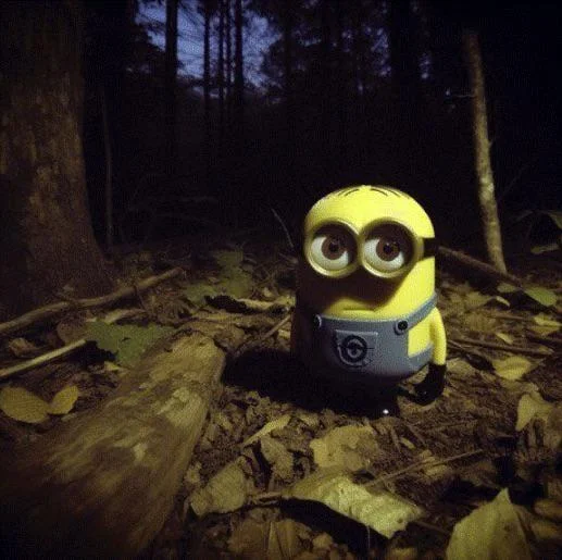 Minion Staring In The Forest — Minion figurine on forest floor at night surrounded by fallen leaves and dark trees
