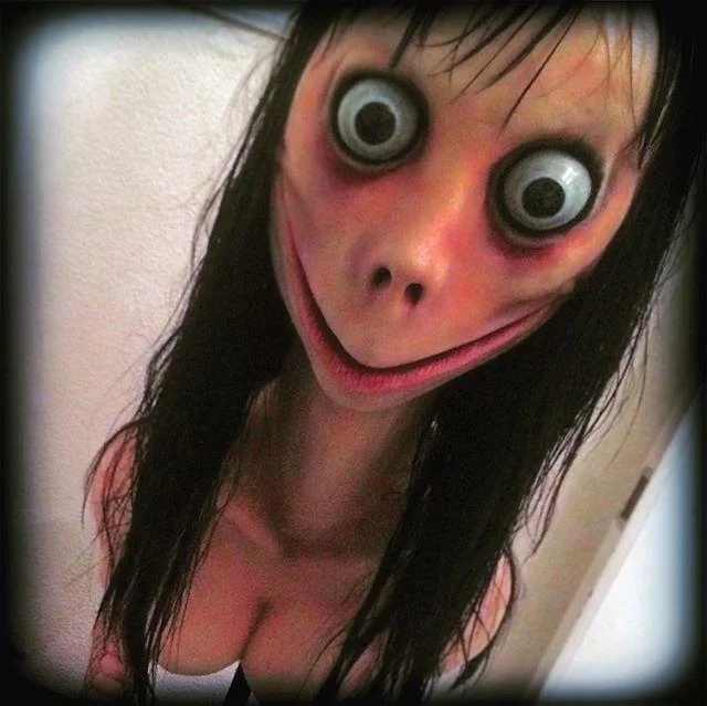 Close-up portrait of Momo sculpture with distinctive large bulging eyes, long dark hair, and pale complexion.