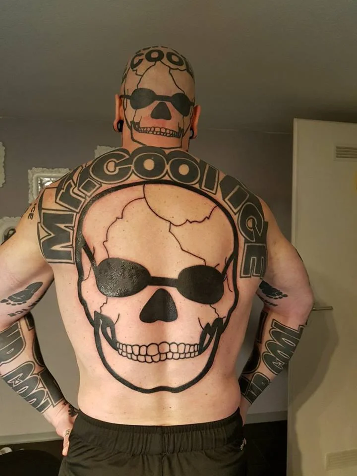 Muscular man's back and shaved head covered in a giant skull and 'Mr. Cool Ice' tattoo