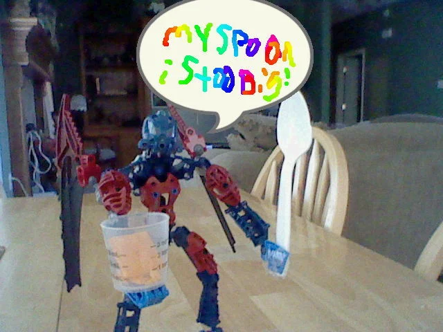 Bionicle toy holding plastic spoon with rainbow My Spoon Is Too Big speech bubble