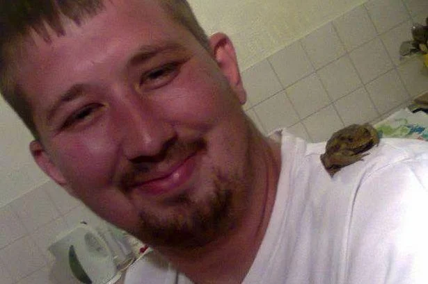 Smiling man in bathroom with a small animal on his shoulder during a NekNominate stunt