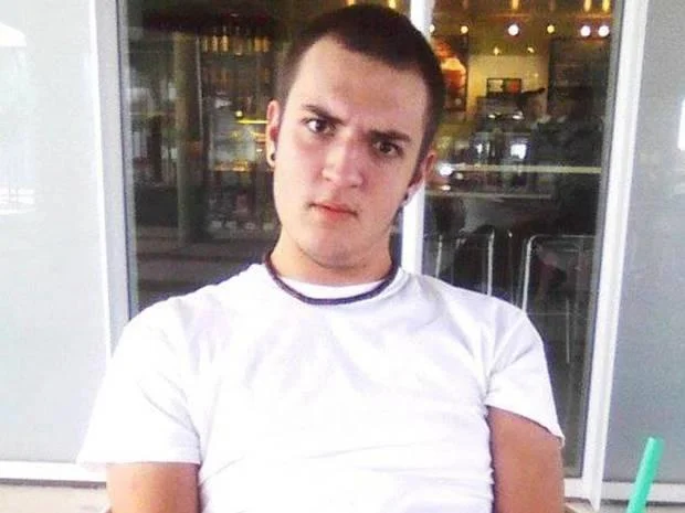 Young man in white t-shirt outside a cafe, linked to NekNominate news coverage