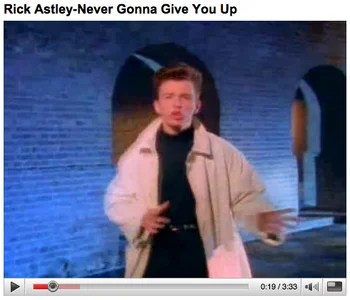 A screenshot of Rick Astley's 'Never Gonna Give You Up' music video playing on YouTube, showing Rick dancing in a tan coat.