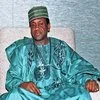 Nigerian Scams — A dignified African man dressed in formal teal traditional Nigerian robes and matching cap in an official setting.