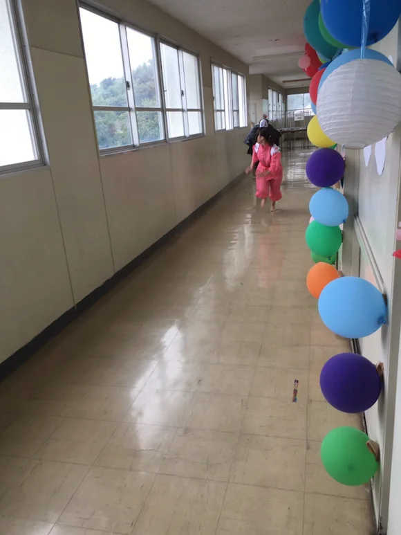 No Face Chasing Chihiro — School hallway with balloons and small figure in pink walking away in the distance