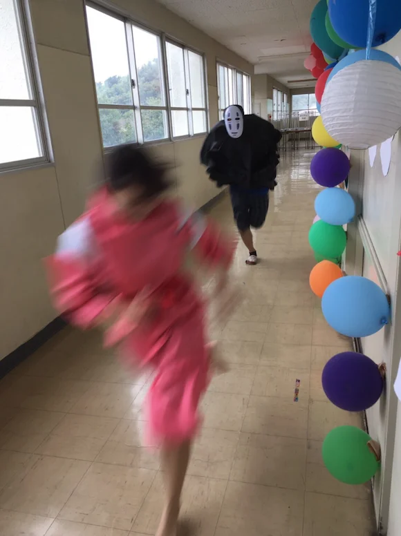 No Face Chasing Chihiro — Vertical photo of costumed Chihiro running from No-Face down decorated hallway