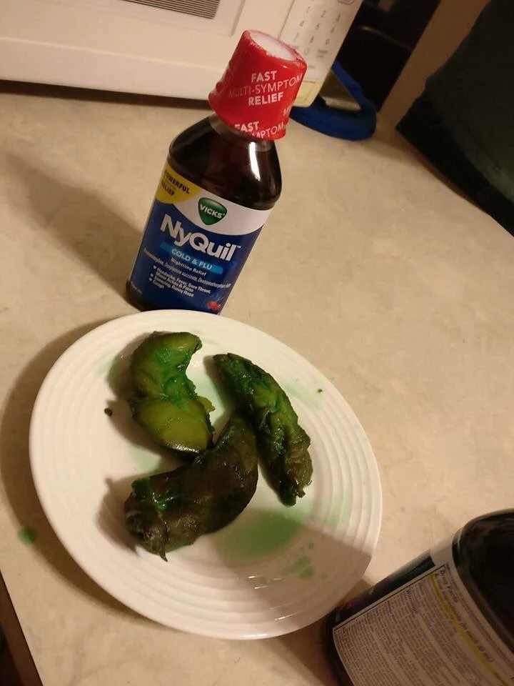 NyQuil Chicken — Plate of green-stained cooked chicken next to a bottle of Vicks NyQuil Cold & Flu