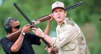 Obama Skeet Shooting Photo — Two men at outdoor shooting range with one holding shotgun and other observing.