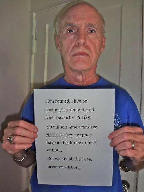 Elderly man holding a handwritten 'We are the 99%' statement in support of Occupy Wall Street