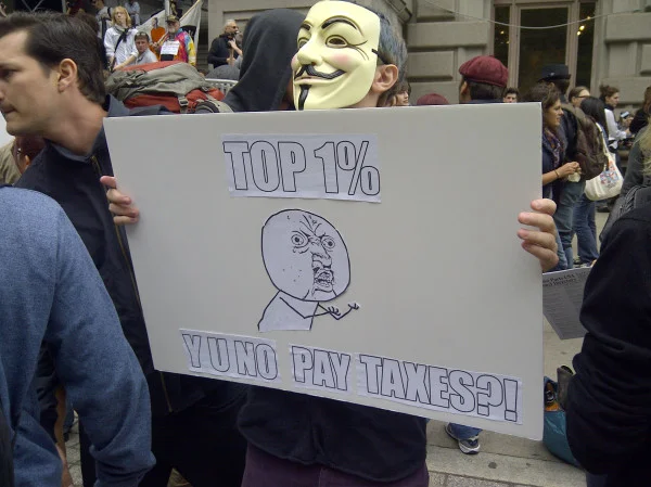 Occupy Wall Street — Protester in Guy Fawkes mask holds a Y U NO meme sign about the top 1% and taxes
