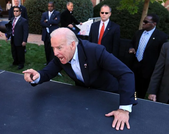 Ok Smart Guy! Let's See YOU Take A Crack At It! — Joe Biden leaning on a dark surface, pointing and shouting, with Secret Service agents in the background