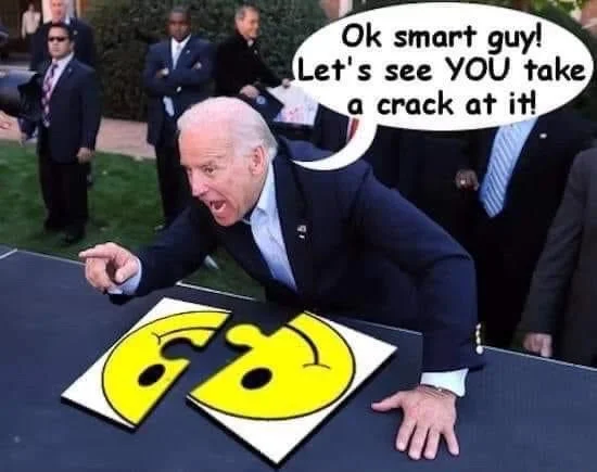 Joe Biden pointing at torn smiley face puzzle with speech bubble 'Ok smart guy! Let's see YOU take a crack at it!'