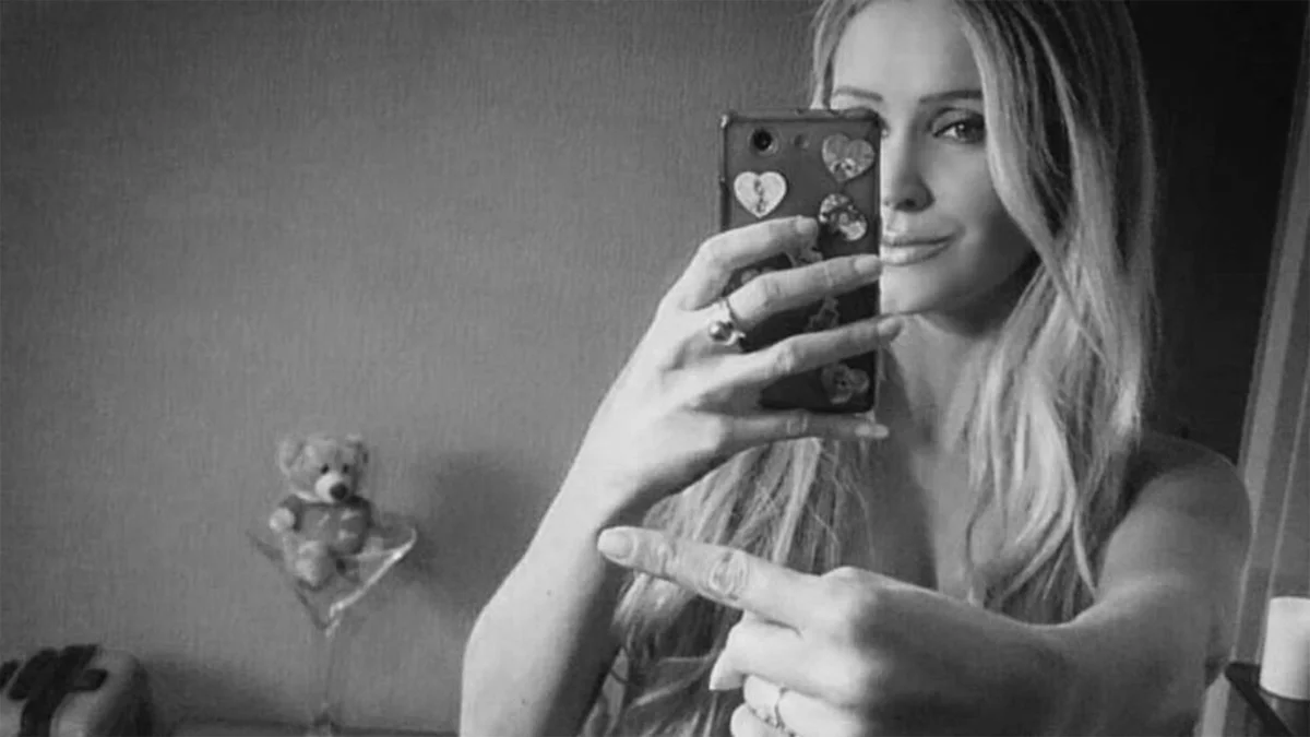 One Finger Selfie Challenge — Black and white mirror selfie of a blonde woman using one finger to censor her nude body while taking a photo