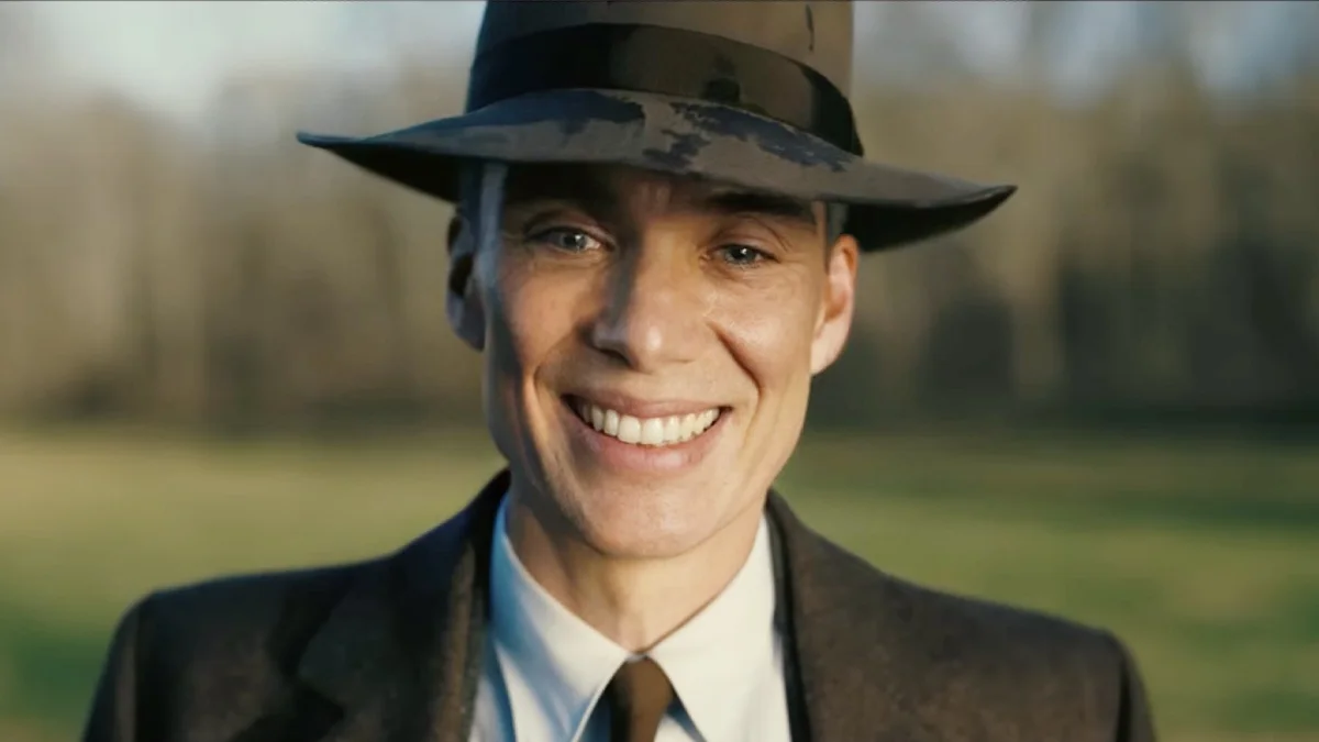 Oppenheimer Smile — Cillian Murphy as Oppenheimer smiling in a fedora hat in a sunlit field
