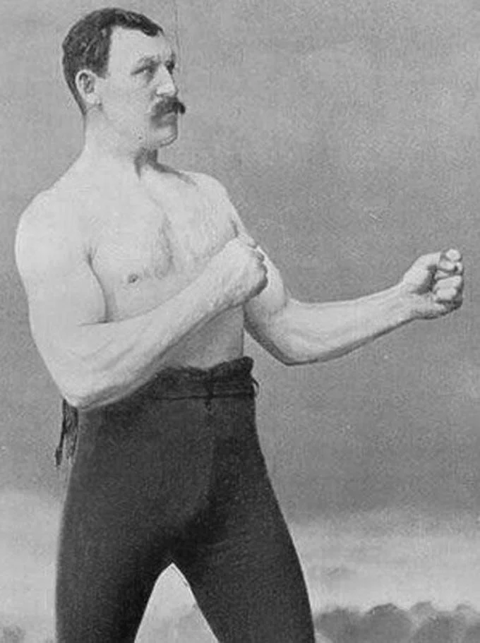 Overly Manly Man — A clean black and white template photograph of the shirtless, mustachioed strongman in characteristic pose without text.
