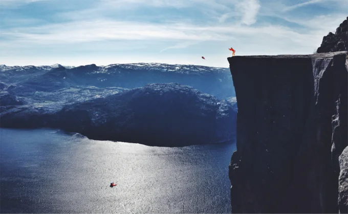 Parents Throwing Baby — Baby thrown from a cliff over a fjord with a kayaker below