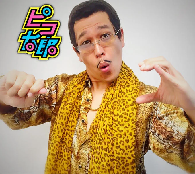 "Pen Pineapple Apple Pen" — Piko-Taro posing with signature hand gesture next to his Japanese name logo