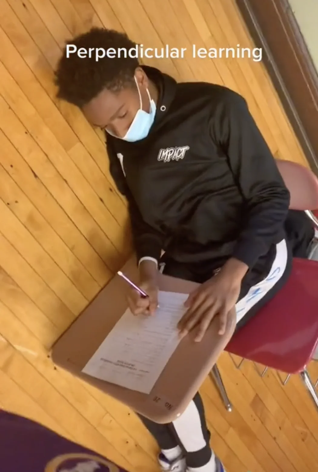 Perpendicular Fueling — Student lying sideways on a chair writing on a clipboard with text 'Perpendicular learning'.