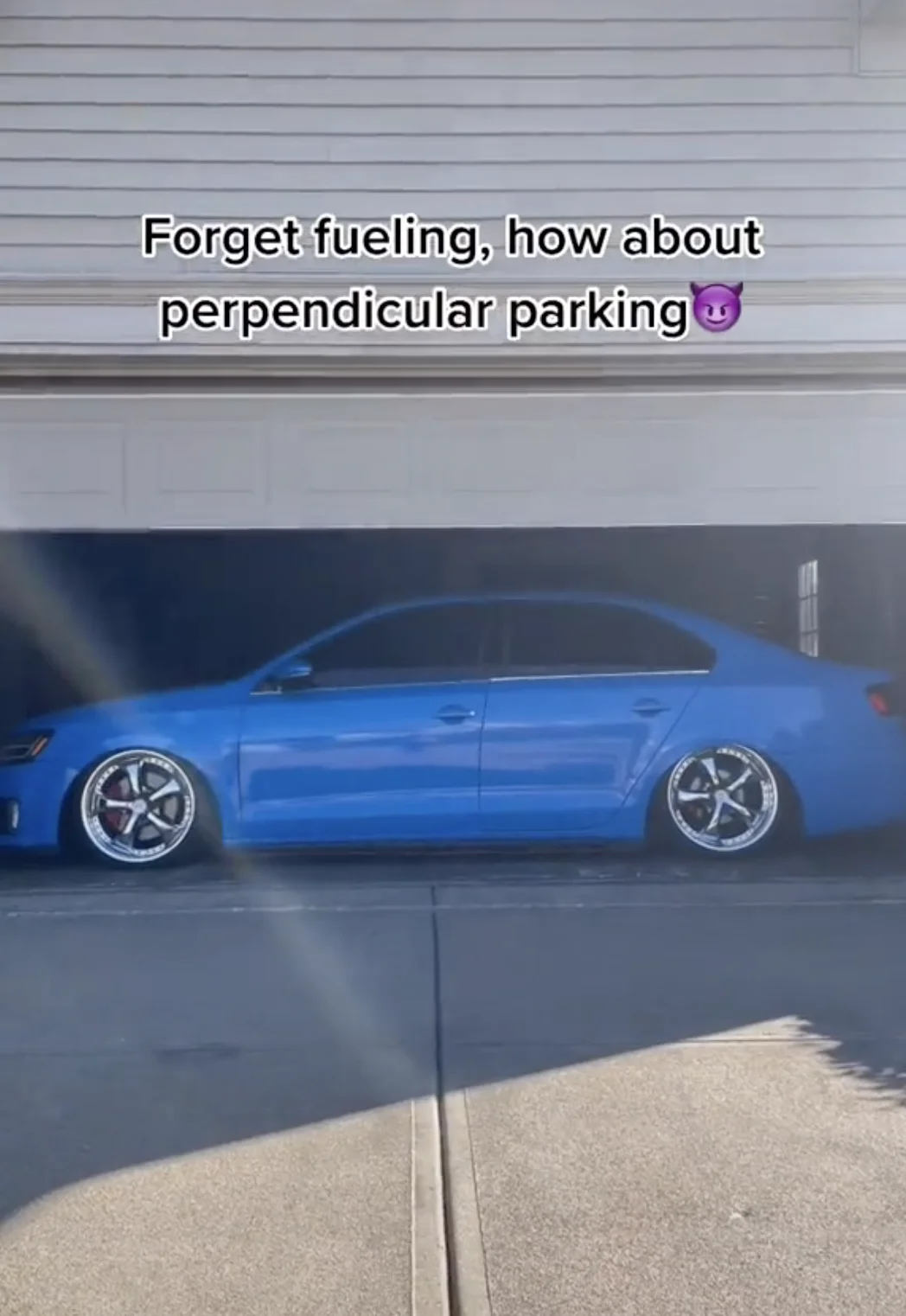 Perpendicular Fueling — Lowered blue VW Jetta parked sideways in a driveway with text 'Forget fueling, how about perpendicular parking'.