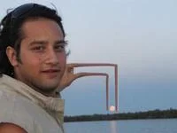 Photoshop Request Threads — A man with shoulder-length hair photographed against a beach landscape where a rectangular structure has been digitally removed.