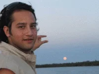 Photoshop Request Threads — A man with shoulder-length hair against a beach landscape where a glowing moon or celestial sphere has been added to the sky.