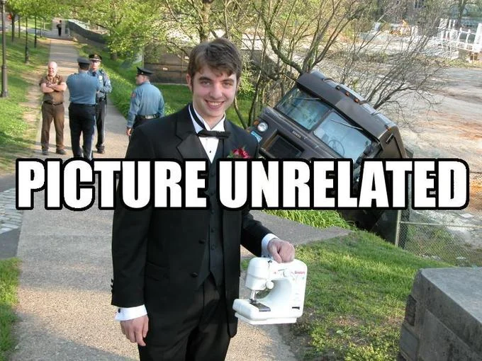 Young man in tuxedo holding a sewing machine with a crashed truck and police in the background, captioned 'PICTURE UNRELATED'