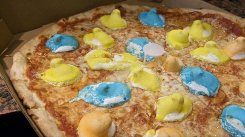 Pizza Crimes — A pizza covered with bright blue and yellow decorative toppings or paint-like substances arranged across the surface.