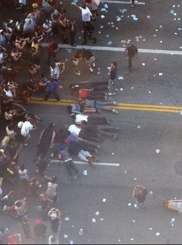 An aerial photograph of a major planking event with numerous participants lying horizontally on a street.