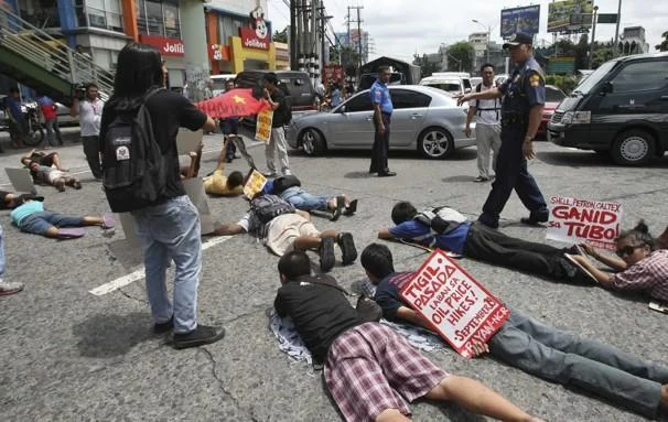 A ground-level photograph of an organized planking event showing multiple people lying face-down horizontally on a paved street.