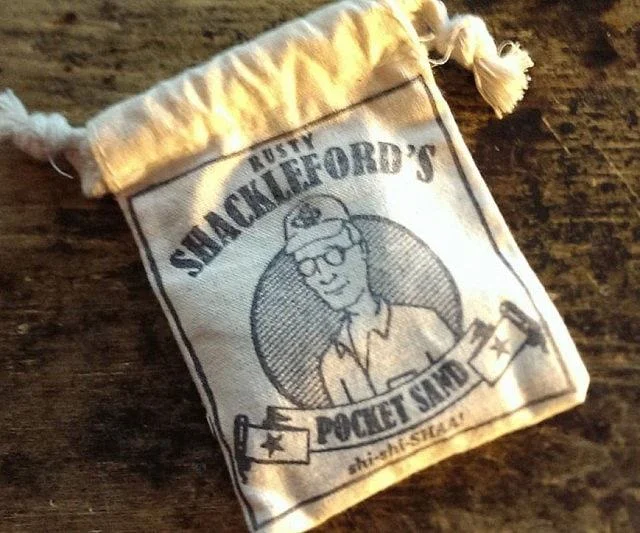 Drawstring pouch labeled Rusty Shackleford's Pocket Sand