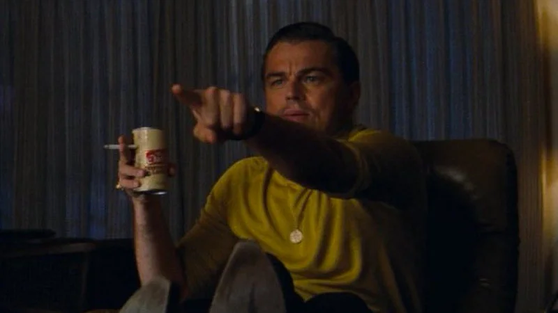 Pointing Rick Dalton — A high-quality film screenshot of Leonardo DiCaprio as Rick Dalton from Once Upon a Time in Hollywood, sitting in a leather armchair