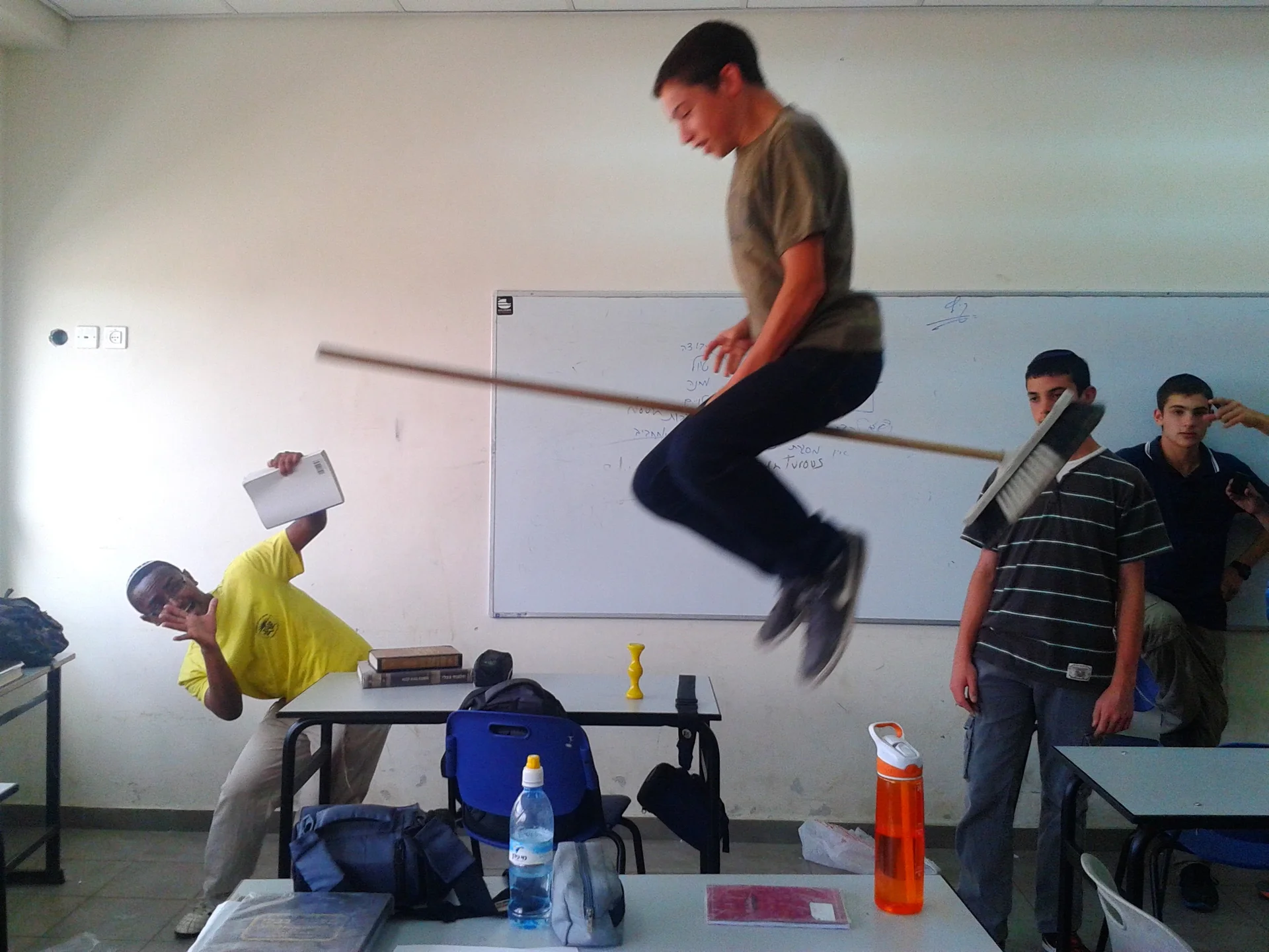 Teenage boy pottering in a classroom while a teacher reacts dramatically