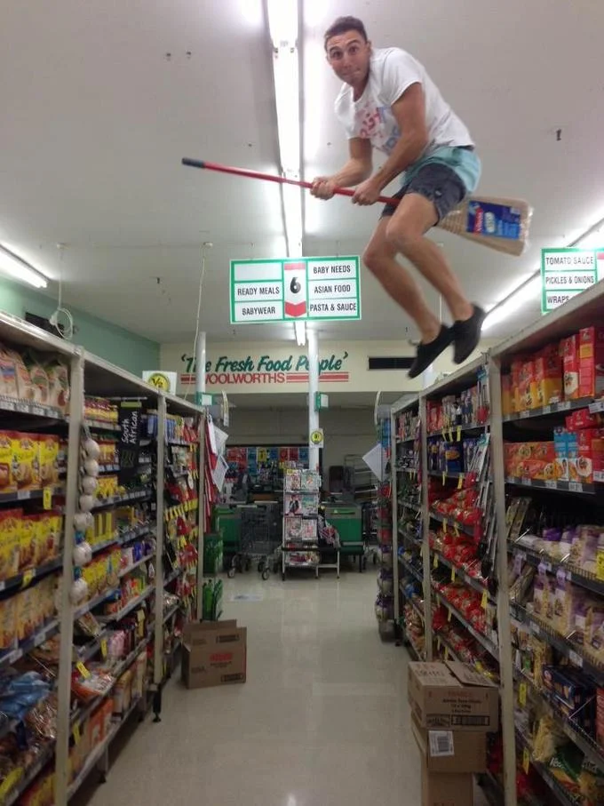 Person pottering on a broom inside a Woolworths supermarket aisle