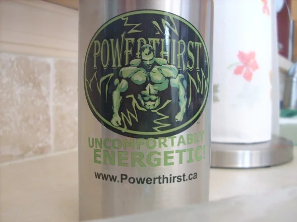Real Powerthirst energy drink can on a kitchen counter with bodybuilder logo and 'Uncomfortably Energetic' slogan