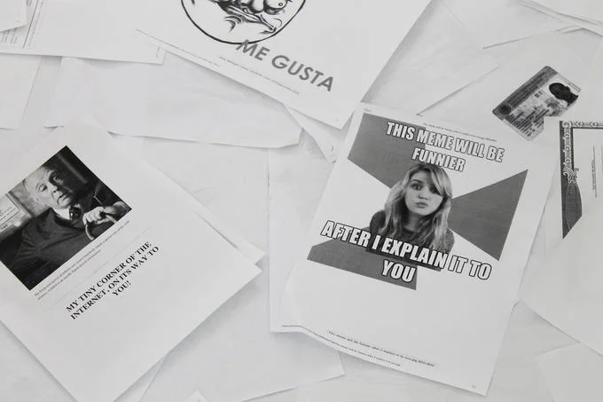 Printing Out the Internet — Printed pages of internet memes including Me Gusta scattered on the gallery floor